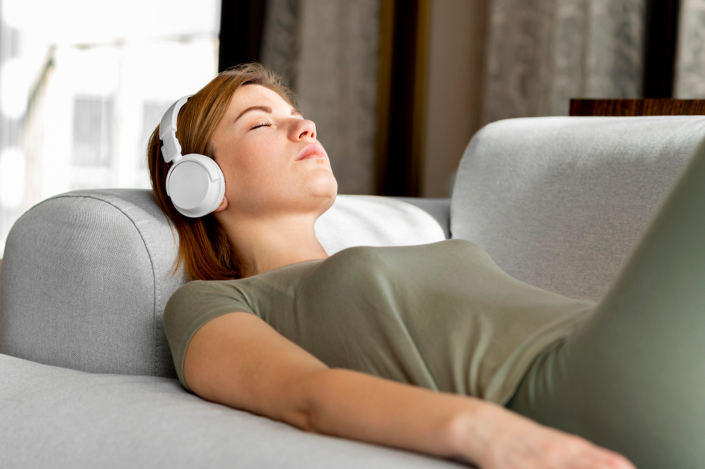 A lady trying to sleep with headphones on and listening to music.