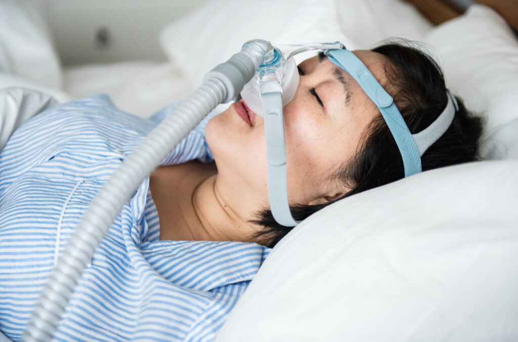 A woman sleeping on a bed with a device to help make her sleep better.