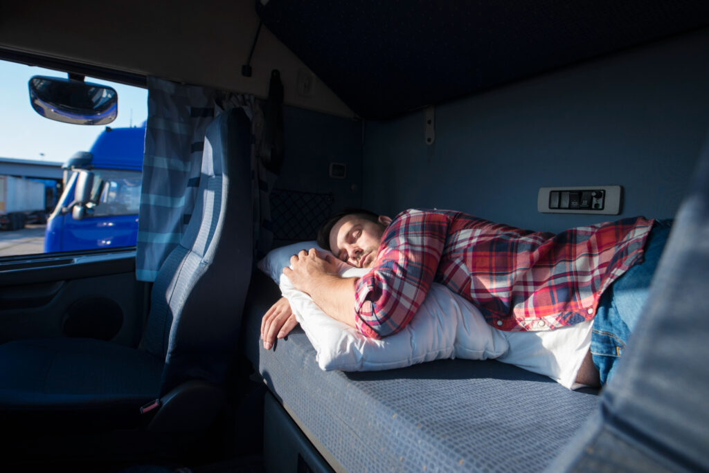 A Young man sleeping in a camper wagon overlooking a parking lot