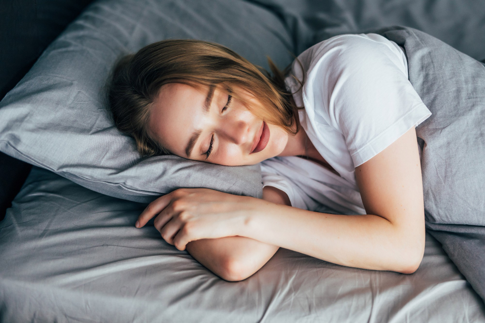 A young lady sleeping with a smile on her face on a white bed