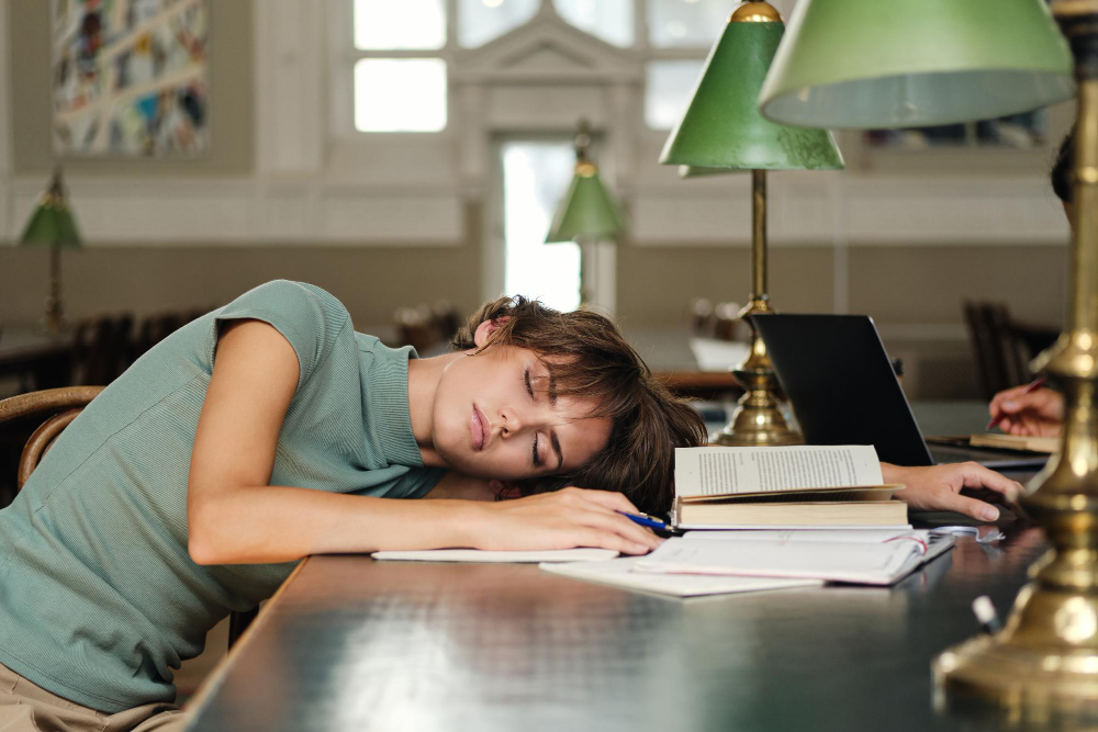 Another university student sleeping with books open on a desk